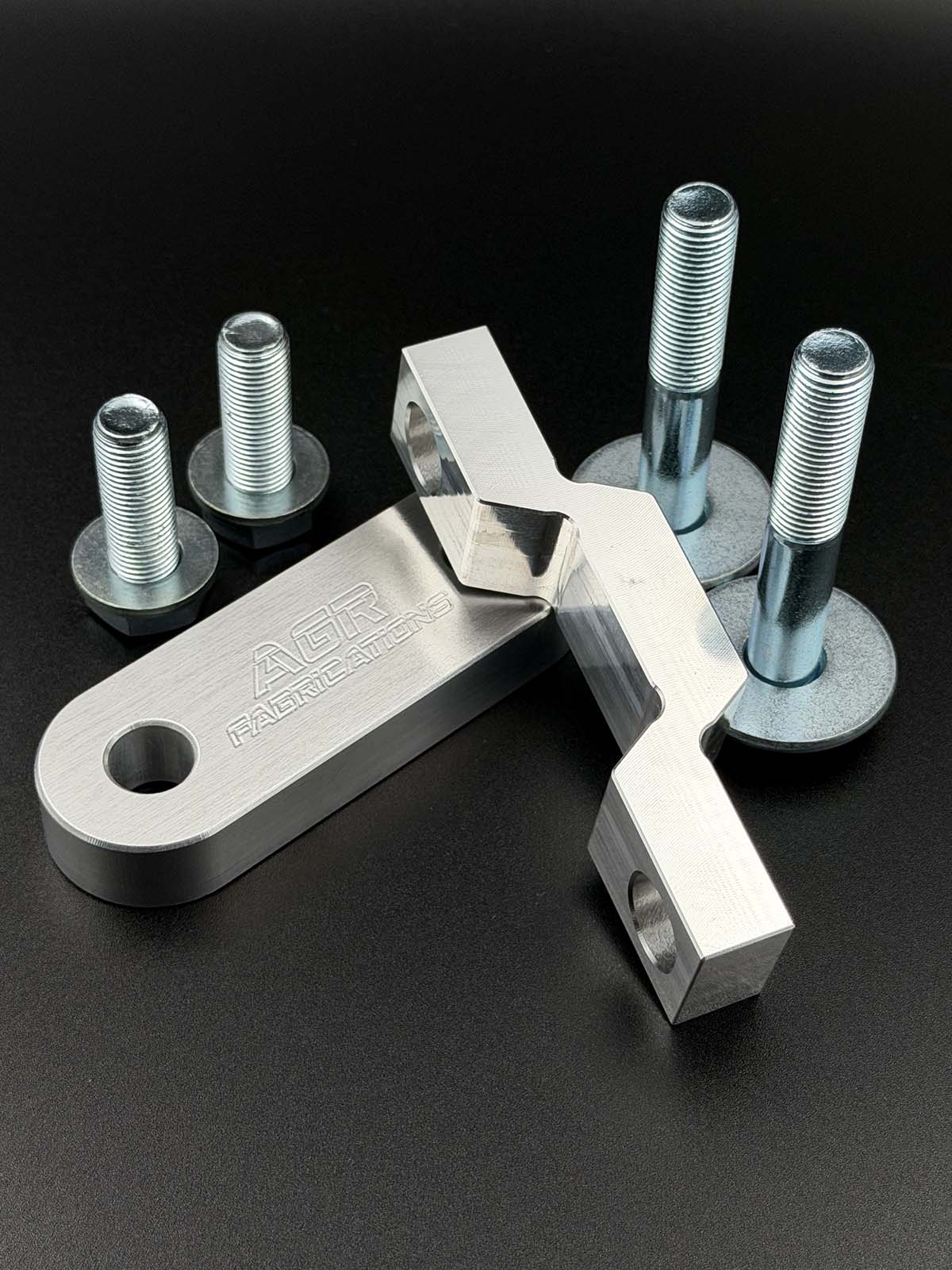 aluminium steering rack spacers displayed on a black background with zinc plated fasteners 